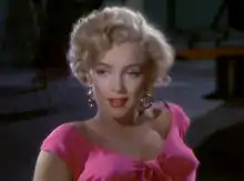 Monroe en Niagara. Un primer plano de su rostro y hombros; ella lleva aretes de oro y una blusa rosa impactante.