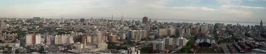 Foto panorámica de los barrios de Montevideo: Aguada, Centro y Cordón, tomada desde la Torre Antel. Se distingue el Palacio Salvo (derecha) y la Estación Central General Artigas abajo a la derecha. Además, a su derecha se encuentra el Puerto de Montevideo que se ubica en la Bahía de Montevideo.