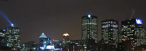 Vista nocturna desde la Place d'Armes; el faro que se ve a la izquierda está situado en la Place Ville-Marie.