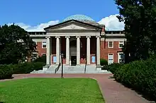  A brick building with a rusted dome and ionic columns.