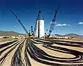 Preparativos para una prueba subterránea. La torre de situación baja el ingenio nuclear en la cavidad excavada; los cables llevan la información a los instrumentos que recogen el experimento.