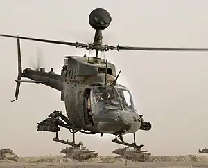 Un OH-58 Kiowa mostrando su mira montada en el mástil, un mísil antitanque y un contenedor de cohetes.