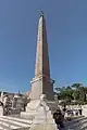 Vista del obelisco con un león en el primero plano.