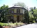Casa de estructura de madera de tamaño modesto pero decorativa, que se observa pintada en colores 'tradicionales' que pueden reflejar el esquema de color original. Casa octágono, Barrington, Illinois (construido en 1860).