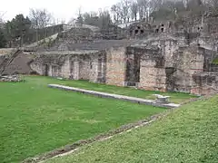 Remanente del pórtico con su estilóbato y una base de columna. El pavimento del pórtico está cubierto con un césped protector.