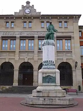 Escultura de San Francisco, al fondo las Escuelas Municipales