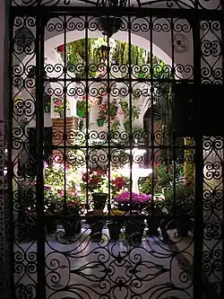 Al fondo, las luces de un patio cordobés visto desde la puerta que da a la calle.