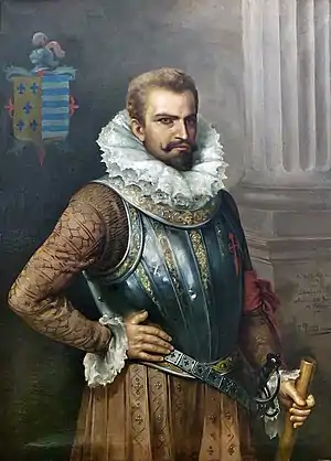 Pintura de un hombre con barba en traje que data de principios del siglo XVI incluyendo un prominente collar, vestido con un pectoral decorativo, con su mano derecha descansando sobre su muslo y su mano izquierda sujetando un bastón o una fusta.