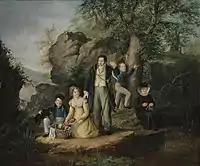 Una familia burguesa de picnic en primer plano y árboles y rocas al fondo