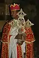 Sacerdote de la iglesia de Yemrehanna Krestos con vestiduras litúrgicas, portando una cruz.