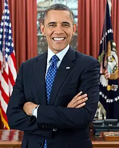 Obama gestures from the podium while campaigning. The front of the podium has a sign that reads "Change We Need" with WWW. BARACKOBAMA. COM below and his campaign logo above.