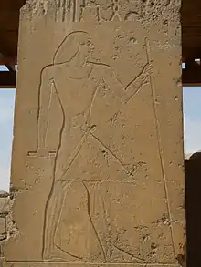 Relief of a man standing holding a staff