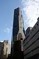 Ground-level view of 70-storey building. The exterior has a reddish hue with dark windows. The building tapers slightly at two points.