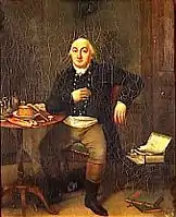 En un interior, hombre sentado a la mesa, pero mirando al espectador de frente, con chaqueta oscura, pantalón ocre y botas hasta la rodilla, negras por abajo y marrones por arriba. Sobre la mesa, un velador parece haber comida.