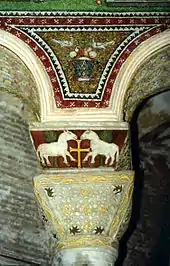 Decoración de mosaico y relieve policromado en los arcos y el capitel y cimacio de una columna en San Vital de Rávena, arte bizantino del siglo VI.