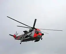 Un helicóptero blanco y rojo en el aire.