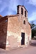 Vista fronto-lateral izquierda de la iglesia parroquial de Sesga (Ademuz), con detalle de la espadaña de dos ojos (2017).