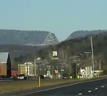 A small town is seen below a mountain ridge which contains a deep V-shaped cut.