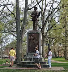 A statue of a soldier with three people walking around the base.