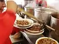 Mesero sirviendo un plato de birria
