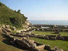 Primeiro plano dos restos do quartel e estábulos, no seu fundo a piscina e o triclínio.