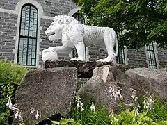 León de cemento en el lado noreste de la iglesia de Sainte-Thècle creado por el sacerdote Maxime Masson.