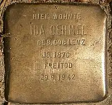 Primer plano del Stolpersteine o piedra de tropiezo hecha en lo que parece bronce y en la que se puede leer: «Hier wohnte Ida Dehmel Geb. Coblenz. JG. 1870 Freitod. 29/9/1942