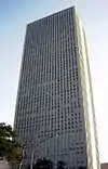 Ground-level view of two grey, rectangular building faces perfectly lined with columns of windows