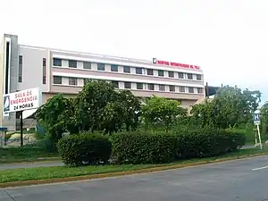 Hospital Metropolitano Dr. Pila al lado norte de la avenida Las Américas, mirando al noreste, en el barrio Canas Urbano