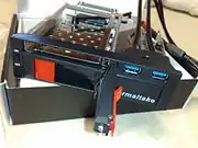 Un rack dual-HDD, hecho como un dispositivo de bahía de 5.25 pulgadas capaz de sostener simultáneamente un disco duro SATA de 2.5 y 3.5 pulgadas, con dos puertos USB 3.0 adicionales