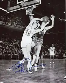 A man wearing a green t-shirt and a green cap with a word "CELTICS" are pointing his hand towards the camera.