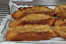 Varias torrijas. Descripción de una torrija físicamente: una rebanada gorda de pan frita de color marrón claro con azúcar y canela por encima