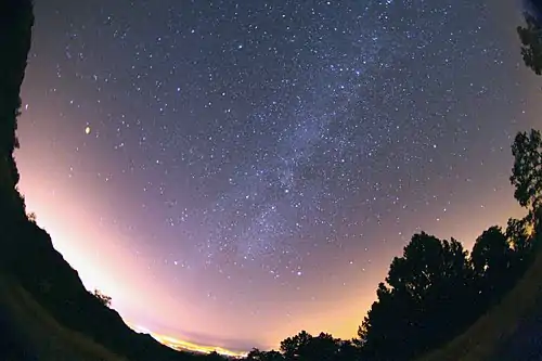 Una vista del cielo completo (luna a la izquierda) muestra la Vía Láctea (a través del centro), que suele ser invisible bajo la luna llena.