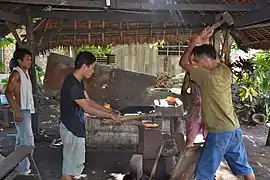 Herreros tradicionales forjando un bolo.