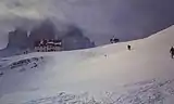 Las Tres Cimas de invierno en medio de las nubes. En primer plano, el refugio A. Loatelli.