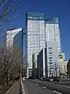 Ground-level view of a three-building complex; each building is white and blue and lined with rows of windows