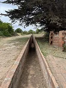 Acceso en ladrillo a tumba en el cementerio de Ciudad Abierta en Ritoque, espacio creativo de la facultad de arquitectura de la Universidad Católica de Valparaíso.