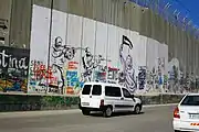 Mural de dos soldados de las FDI apuntando a una mujer palestina