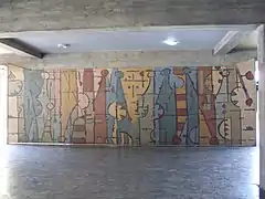 Mural de Oswaldo Vigas llamado Un elemento - personaje vertical en evolución horizontal ubicado en el edificio del Rectorado, vestíbulo de entrada.