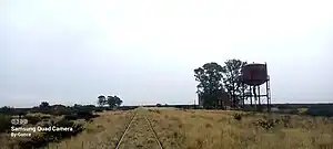 Tanque de hierro junto a la usina y cisternas. Ambas construcciones son vistas como faros a la distancia.