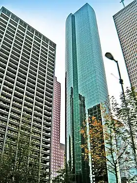 Tall, thin, glass tower with large, rounded outset on one side and strong vertical lines.