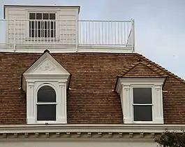 The roof of a house with a widow's walk on top, consisting of a small room surrounded by railing