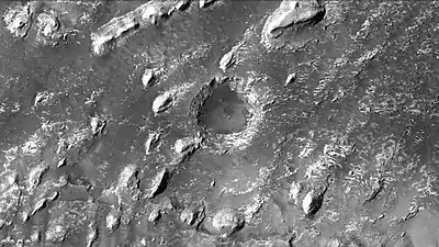 El cráter muestra capas en forma de buttes (cerros muy verticales aislados) dentro de un cráter pequeño, vistos por la cámara CTX. (Nota: ampliación de la imagen anterior de Crommelin)