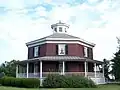 Casa de ladrillo perfectamente octogonal con terraza, techo inclinado y farol. Casa octágono Wilcox, Camillus, Nueva York (construido en 1856).