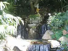 Una pequeña cascada con una estatua de  Krishna.