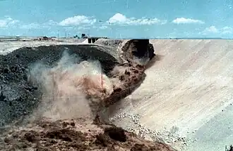 Ahora la presa está rota y el agua fangosa fluye violentamente por la cara de la presa.