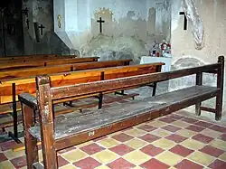 Detalle de bancos de madera y piso de ladrillos hidráulicos en la iglesia parroquial de Arroyo Cerezo, Castielfabib (Valencia).