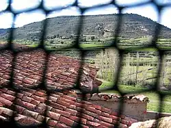 Vista parcial de la vertiente oriental del tejado de la iglesia parroquial de Arroyo Cerezo, Castielfabib (Valencia), desde la torre, con la Muela del Royo al fondo.