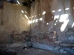 Vista interior de la ermita de San Pedro en El Cuervo (Teruel), con detalle de baldosas apiladas, correspondientes al piso antiguo de la parroquial.