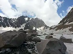 Piedras y guijarros descansando sobre un glaciar con las montañas al fondo.